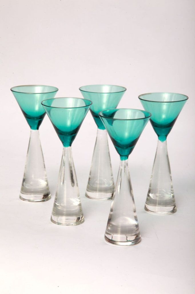 A set of five glasses that are all the same. Each one features a spherical base, a long transparent stem that tapers to the top, and a little blue-tinted triangle-shaped bowl.