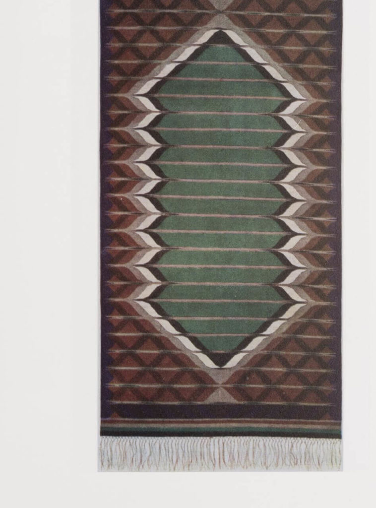 "A woven tapestry rug. A green longitudinal green shape is intercut by horizontal brilliant lines in a regular pattern. The form is situated in the center. A consistent pattern of black squares on a brown background surrounds it. "