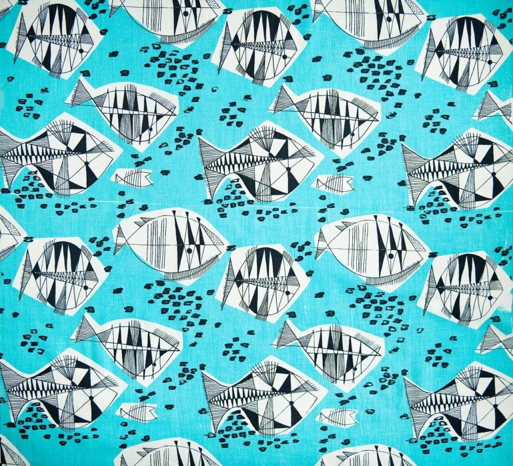 A geometric textile pattern. It shows stylised fish shapes of different sizes drawn in thin black lines on a turquoise background. Each of them has geometric patterns in it. There are black dots between the fish.