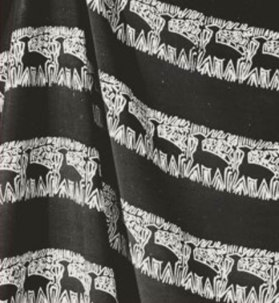 A piece of black fabric with a black and white decorative pattern showing animals that look a little like alpacas.