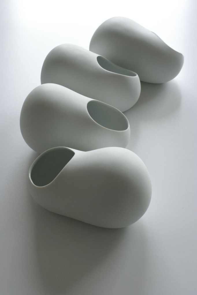 Four ceramic dishes that look like oblong stones with large round holes on top. These holes take up half the surface of each vessel.