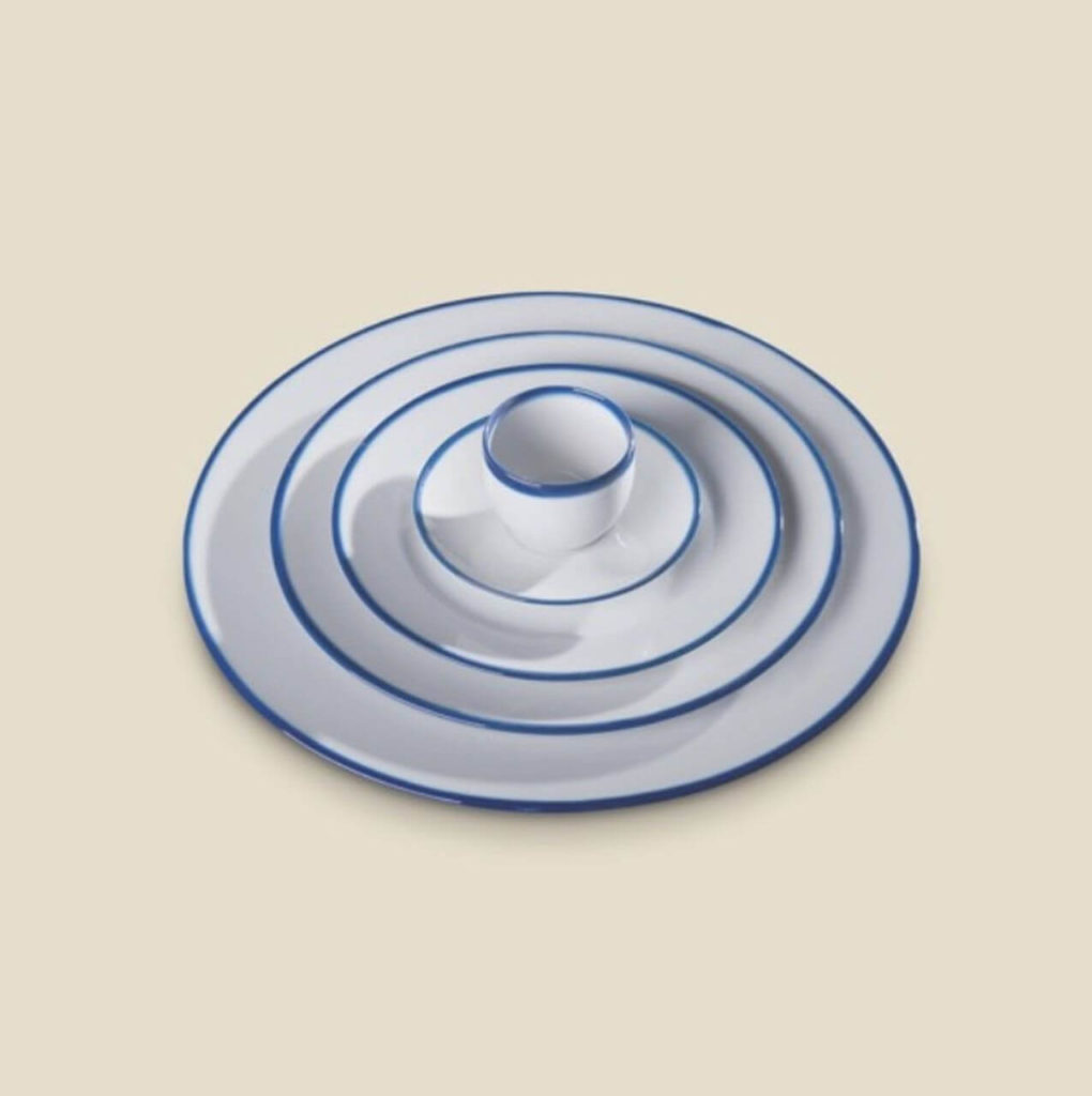 A tiny white cup with a blue border on the plate. The plate is white but has numerous blue central circles, evenly spread. The whole thing resembles a stone thrown into the water.